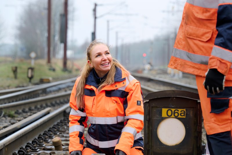 Smilende kvinde i sikkerhedstøj ude i sporet